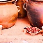 Vasijas de barro con vasos, frutillas e ingredientes para bebidas tradicionales