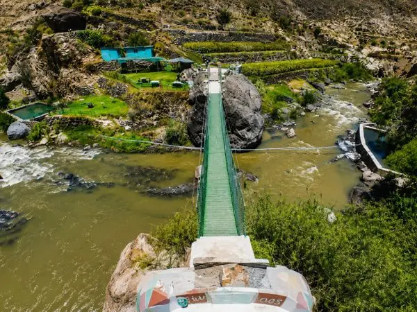 Ingreso al centro arqueológico de Yura en Arequipa con puente peatonal y paisaje natural
